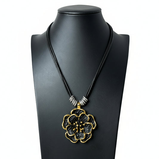 Black necklace with a gold pendant on a black mannequin bust against a white background