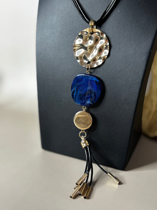 Montana black cord necklace featuring a gold pendant with a blue stone and gold-tipped tassel.