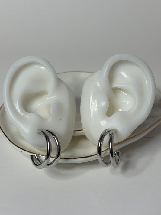 A pair of silver stainless steel hoop earrings displayed on a white surface.