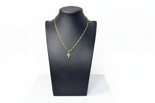 A gold-colored stainless steel necklace displayed on a black mannequin bust, with a cross pendant featured prominently at the end of the chain.