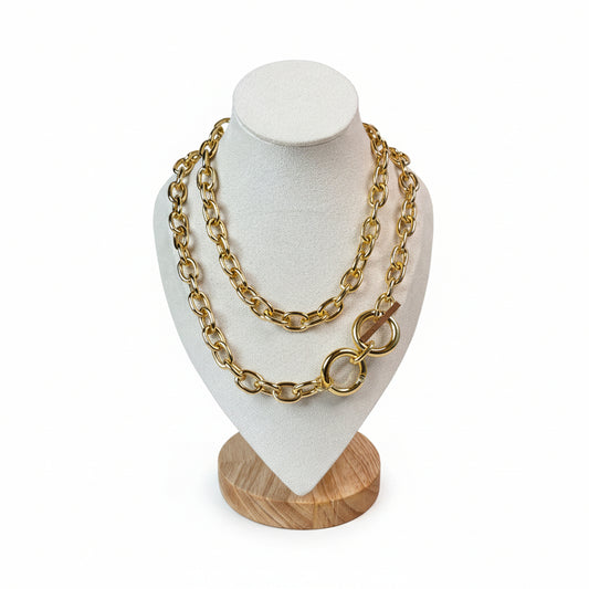 Two gold-colored chunky link necklaces displayed on a mannequin, with one designed as a choker and the other as a Y-style necklace with a pendant.