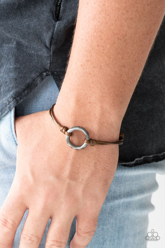 Urban Outsider Brown Urban Bracelet. Shiny brown cording knots around a faceted gunmetal hoop, creating an edgy urban centerpiece atop the wrist. Features an adjustable sliding knot closure. Sold as one individual bracelet.
