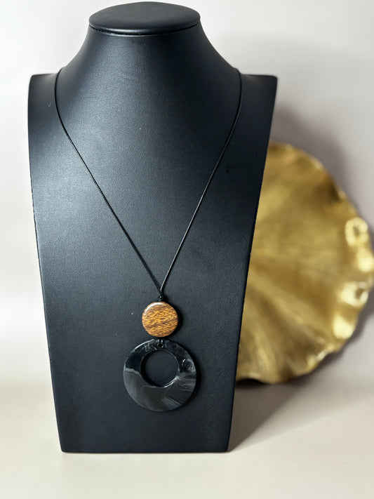 Black Aura Knot cord necklace featuring wooden beads and an acrylic tassel.