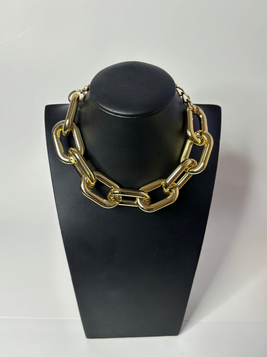 Power irregular chunky link metallic choker necklace in gold displayed on a pedestal mannequin.